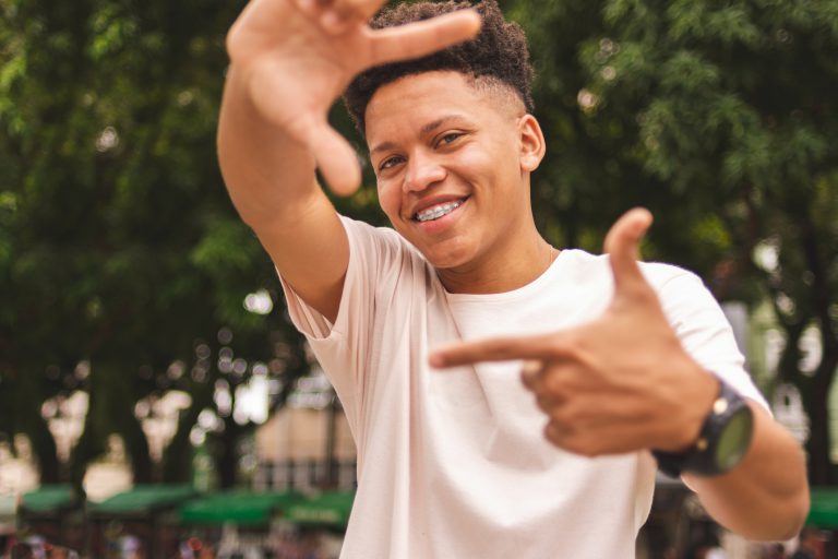 Portrait of a Brazilian guy doing frame with fingers wearing braces and smiling