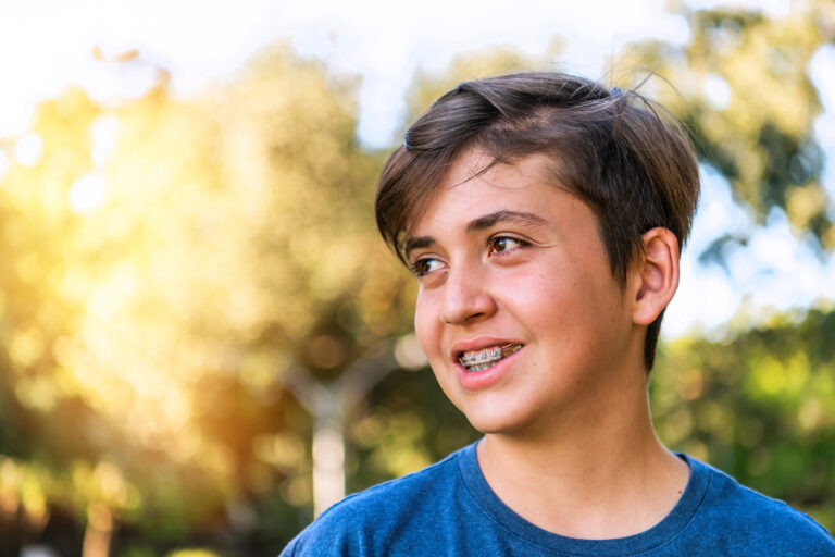Smiling teenage boy wearing braces looking away